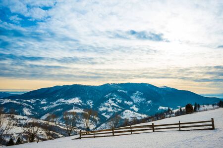 Beautiful panorama of the mountain ranges covered with snow and divided into hiking trails overlooking the cloudy sky and sunset. Place for advertising. Mountain tourism conceptの写真素材