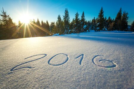 The inscription 2016 on snow against the background of the forest and hills on a sunny frosty winter day. The concept of winter time and new year and Christmasの写真素材
