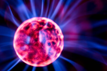 Decoration lamp in shape of plasma ball with red and blue electrodes over black background, close-up. Modern unusual types of illumination conceptの写真素材