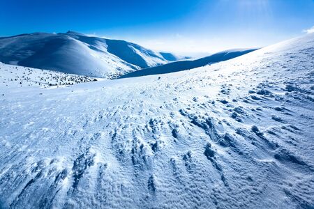 Landscape of snow winter valley surrounded by hills and sun in above on clear winter day. View of...