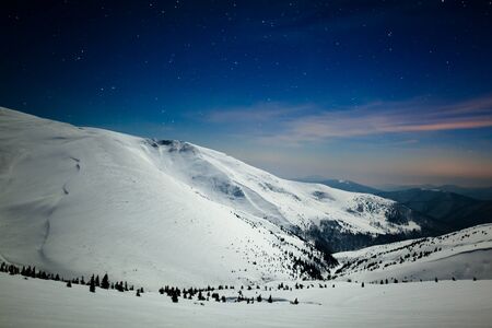 Bewitching beautiful view of the mountains and hills in the snowy valley in the late evening. Beauty concept of winter countryside and winter weekend relaxation. Copyspaceの写真素材