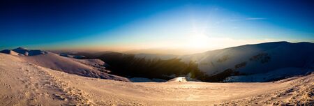 Bewitching beautiful view of the mountains and hills in the snowy valley in the late evening. Beauty concept of winter countryside and winter weekend relaxation. Copyspaceの写真素材