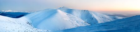 Bewitching beautiful view of the mountains and hills in the snowy valley in the late evening. Beauty concept of winter countryside and winter weekend relaxation. Copyspaceの写真素材