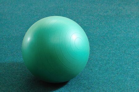 Green ball for fitness on azure background, tools for sports and yoga, equipment for the gymの写真素材