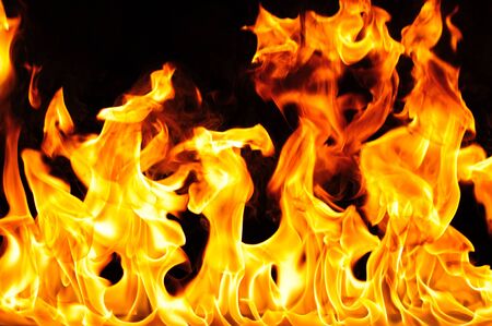 Tongues of flame rise up on black background. Fire at bottom of picture, close up photo