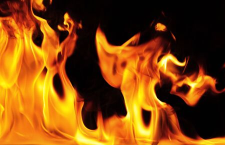 Close-up photo of bright orange yellow flame on a black background, fire burns backdrop