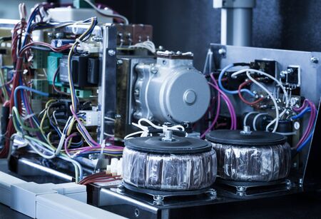 Assembled circuit of electrical relay inside metal case on steel frame with two inductance coils, several boards, switches and resistorsの写真素材