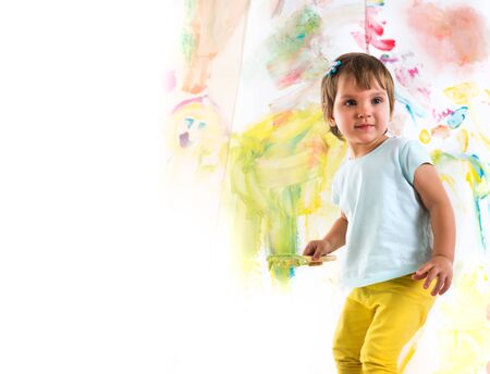 Little girl holds brush in hands and drawsの写真素材