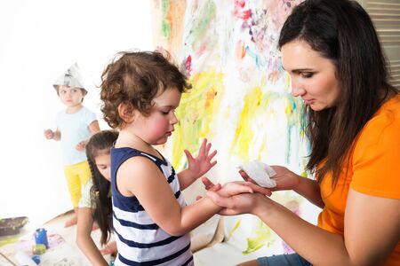 Woman and babies drawing while sitting at tableの写真素材