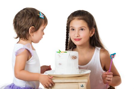 Two little girls near the cake on whiteの写真素材