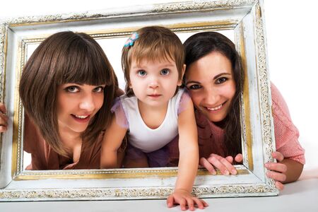 Two girls and child holding wooden white frameの写真素材