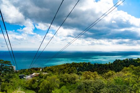 Aerial view of funicular paths pass by picturesque thickets of trees in a gorge on background of sea covered with dense fog. Concept of exotic relaxation and enjoyment of natureの写真素材