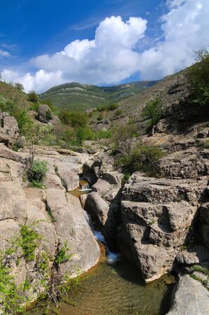 Mountain stream flows on the rocks through stones. Rocks changed color caused to contact with waterの写真素材