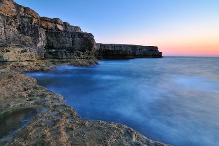 Beautiful sunset over wavy stormy Black sea rocky coastline in Crimea on summer day. Natural...