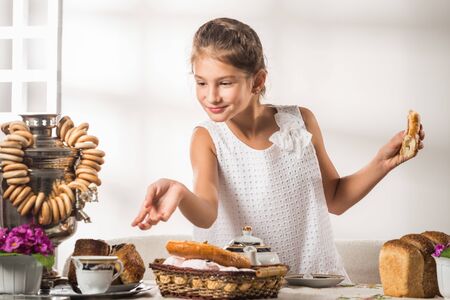 Cute little girl in a white sundress drinks teaの写真素材