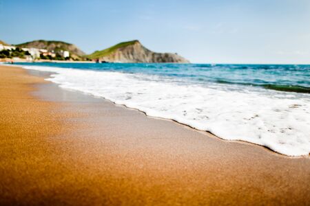 Sandy beach with mountains on the background. The mountains are covered with grass, and sheer cliffs from the sea.の写真素材
