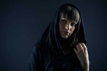 Mysterious lady standing against blue background.の写真素材
