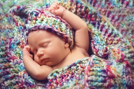 Newborn baby sleeps in a knitted scarfの写真素材