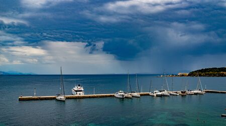 View of many white yachts near pier in Ionic sea near Corfu island, Greece. Beautiful landscape of boats in blue water, sunny day.の写真素材