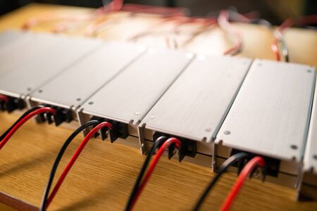 Close-up metal AC-DC power supply with wires lie on wooden table in anticipation of further installation in the production of computer equipment for specialized enterprises. Concept of high-tech powerful equipmentの写真素材
