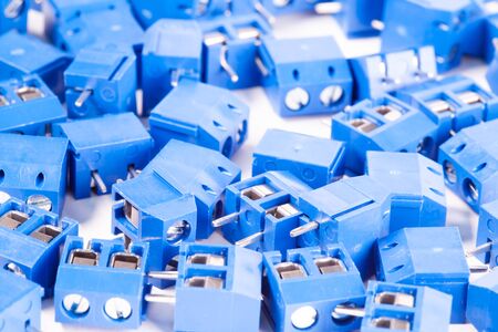 Close-up small blue connector parts lie on a white background. Concept for the production of...