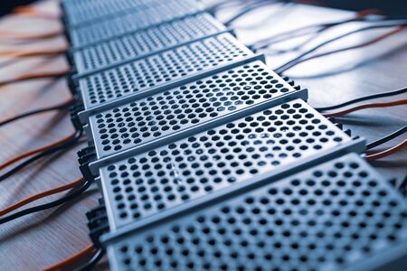 Close up of the metal mesh cases of power supply and wires are on a wooden table at the production...