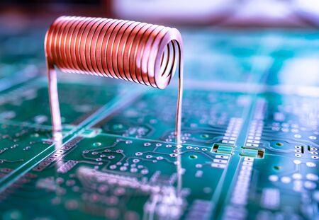 Closeup twisted copper wire stands on a green microcircuit. Computer hardware concept. Factory for...