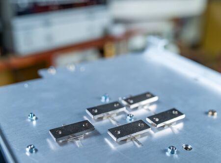 Close-up of five metal plates screwed to a large iron platform. Concept of details for the production of industrial equipment and medical or military equipmentの写真素材