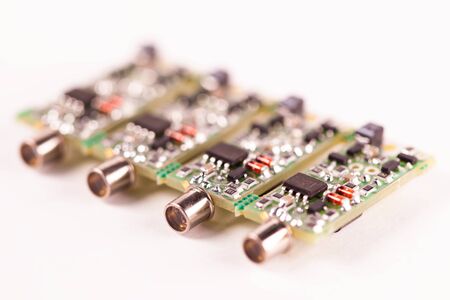 Close-up of four small microcircuits PCB with the output for the wire lying on a white table....