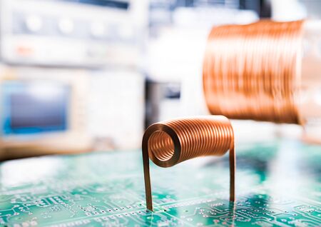 Close-up A lot of skeins of twisted copper wire are standing on a green microcircuit. Factory concept for the production of powerful oscillatory circuit and high-frequency componentsの写真素材