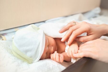 Mother hands care baby on white lace sheets. Sweet child resting in shelf in the dresser. Concept of sleeping infant.の写真素材
