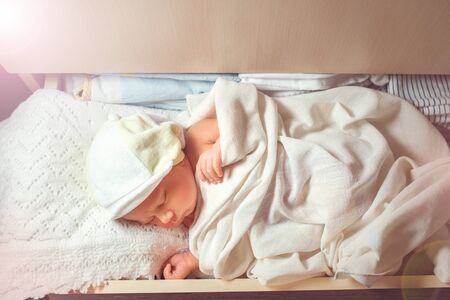 Close up of cute newborn baby taking nap on white lace sheets. Sweet child resting in shelf in the...