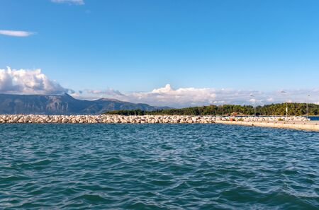 Long white rocky pier in Ionian sea with clear water. Greece. Beautiful lanscape, mountains on...