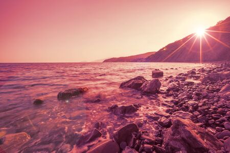 Beautiful seascape which waves splashing along a rocky beach against the backdrop of high mountains...