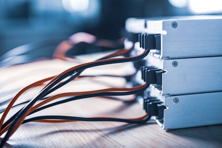 Close-up metal cases for storing power supply with wires stand in a stack on a wooden table. The concept of high-tech equipment for a military spy equipmentの写真素材