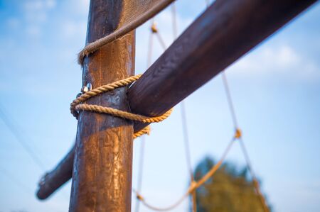 Closeup it is a wooden knot interwoven with a rope on the mast of the ship against the background of...