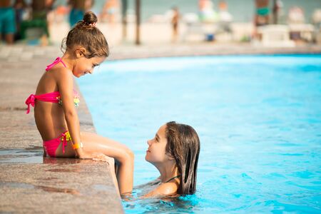 Side view little girls sisters swim in the poolの写真素材
