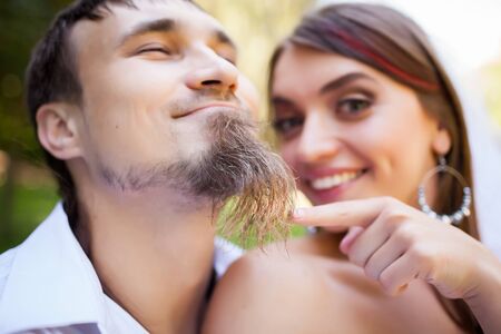 Cheerful bride brushing groom beard.