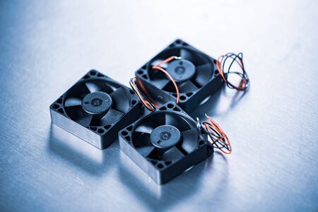 Close-up of three small computer coolers with wires lying on a table on a gray background. Computer...