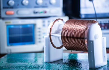 Close-up large and small coils with copper wire stand on a green microcircuit at a factory of classified military equipment. Super secret high-frequency components and equipment conceptの写真素材