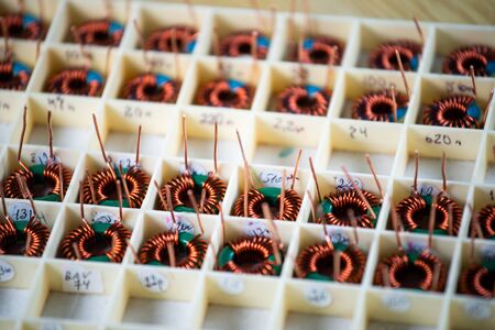Many twisted copper coils lie in the compartments for the further production of electronic equipment. Factory concept for the production of medical equipmentの写真素材