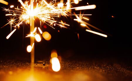 Close-up of golden blurry sparks burn in the dark from the light of festive candles. The concept of fireworks and congratulations on the holidays and happy new year. Copyspaceの写真素材