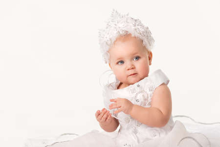 Close-up art portrait of a charming little blue-eyed girl in a white dress personifying winter on a white background. New Year holidays concept and children's love for Christmasの写真素材