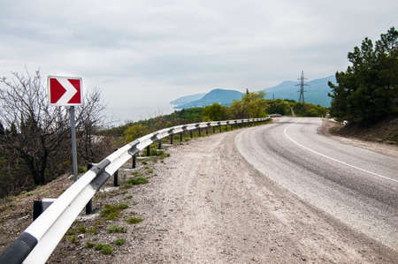 Highway near the coastline. Overcast weather. The road against the backdrop of the mountains.