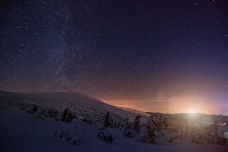 Mystical view of the snowy hills in a mountain valley in winter against the setting golden sun with...