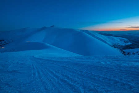 Bewitching beautiful view of the mountains and hills in the snowy valley in the late evening. Beauty...