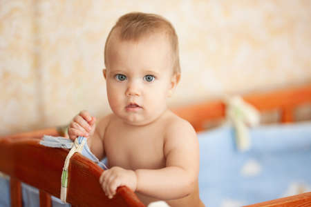Naked happy baby standing in crib.の写真素材