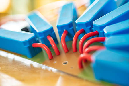 Close-up of a large green microcircuit with red HI-voltage wires and blue relays connected to it at...