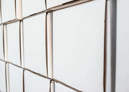 Side view of white paper boxes in rows, minimalistic design objects. Wall with cardboard square...
