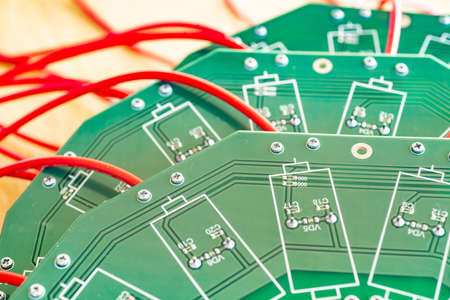 Close-up of a large green microcircuit with red HI-voltage wires and blue relays connected to it at...
